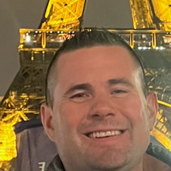 Eric Vincent in front of the illuminated Eiffel Tower at night